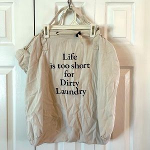 Cream color laundry bag with handles. Drawstring cord closure.